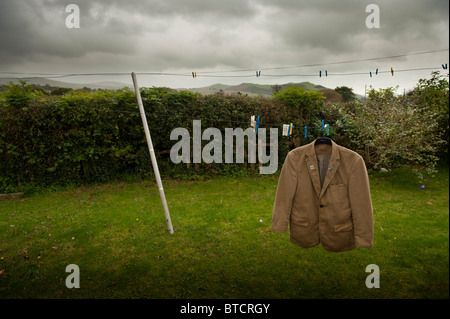 eine alte braune Jacke eine Wäscheleine hängen, in einem Garten, trüben Tag, Wales UK Stockfoto