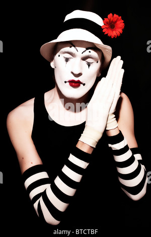 Schlaf-Mime in weißen Hut mit roter Blume auf einem schwarzen Hintergrund Stockfoto