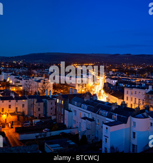 Regency Buildings und beleuchtete Straße im Stadtzentrum von Cheltenham in der Abenddämmerung mit Ampelpfaden, Gloucestershire, England. Stockfoto