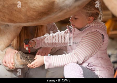 kleine Mädchen, die Reinigung der Hufe eines Ponys Stockfoto