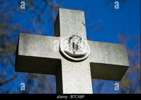 Graue Steinkreuz mit einem Relief von Jesus auf einem Friedhof in München, Deutschland Stockfoto