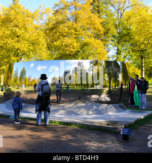 Besucher, die in den Kensington Gardens sind, sehen reflektierte Bilder von sich selbst in einem der Anish Kapoor Sky Mirrors C Curve London England UK Stockfoto