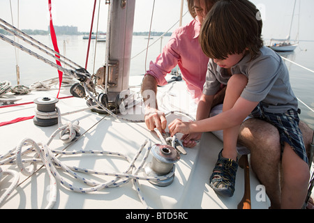 Vater und Sohn an Bord der Yacht mit Seil Stockfoto