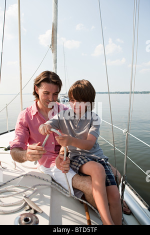 Vater und Sohn an Bord der Yacht mit Seil Stockfoto