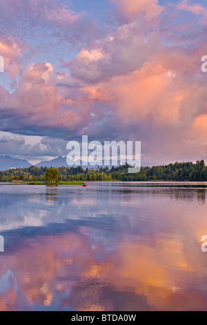 Paar mit rosa Wolken bei Sonnenuntergang, Downtown Anchorage, Alaska, Sommer im Wasser reflektiert in Westchester Lagune am Kajak Stockfoto