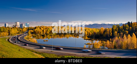 Malerische Aussicht von Minnesota Blvd. Verkehr entlang Westchester Lagune an einem sonnigen Tag mit der Innenstadt von Anchorage in der Ferne, Alaska Stockfoto