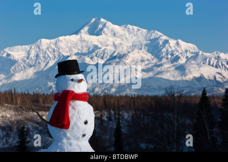 Schneemann rot Schal und schwarzen Hut sitzt auf einem Hügel mit Mount McKinley in den Hintergrund, Denali Nationalpark, Alaska Stockfoto