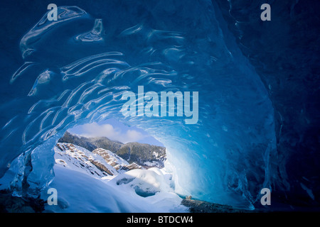 Blick aus dem Inneren eine Eishöhle nach außen auf die schneebedeckte Landschaft, Mendenhall-Gletscher in der Nähe von Juneau in Alaska, Winter Stockfoto