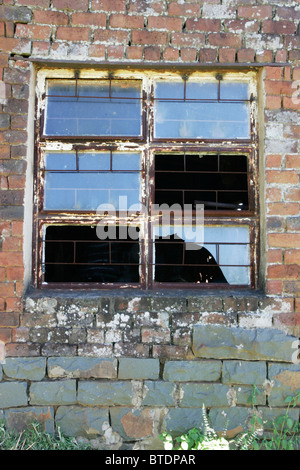 Ein Metall Fensterrahmen mit einigen gebrochenen und fehlende Glasscheiben Stockfoto