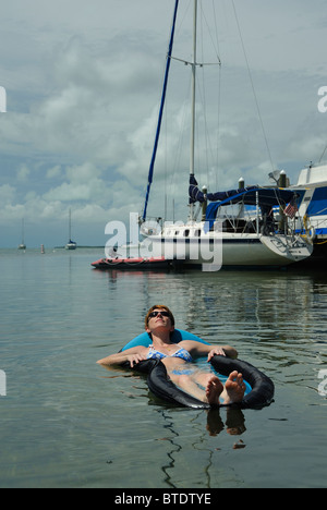 Frau trägt schwarze Sonnenbrille entspannend auf einer Luftmatratze in einer Bucht von Key Largo, Florida, USA Stockfoto