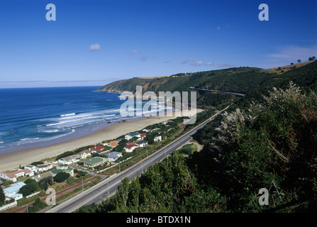 Die Küstenstraße entlang einer Häuserzeile am Strand von De Hoek an der Südküste von Cape Stockfoto