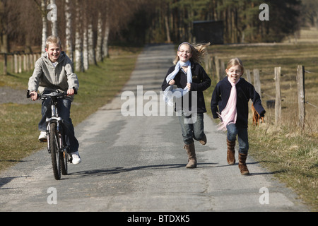 Drei Geschwister auf ihrem Weg auf einer Landstraße Stockfoto