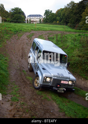 Silbernen Landrover Defender fahren ein sehr steil und sehr rutschiger Abhang hinunter bei Domaine d'Arthey Estate, Belgien Stockfoto