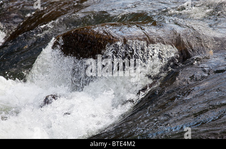 Scharfe und klare Aufnahme eines reißenden Flusses über Felsen Stockfoto