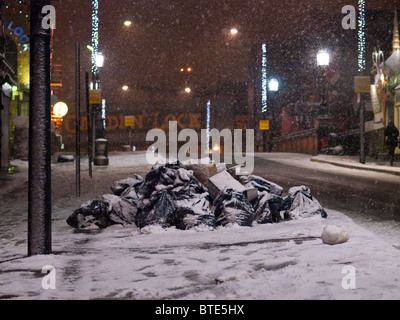 Müll auf einer verschneiten Straße in der Nacht in Camden Town, London, England, UK Stockfoto