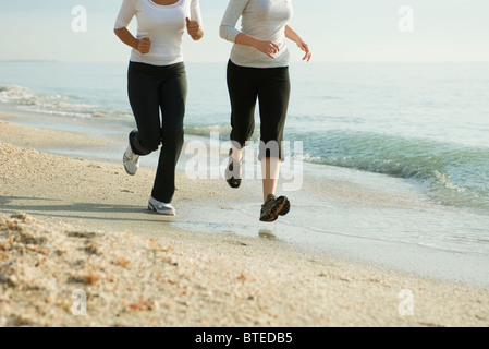 Freundinnen laufen am Strand, beschnitten Stockfoto