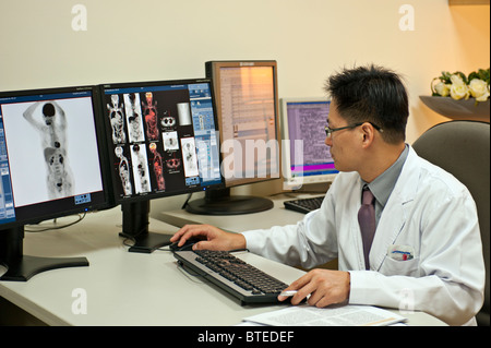 Arzt mit Blick auf PET CT diagnostische medizinische Scanner Bilder auf Computer-Monitore im Krankenhaus Büro Stockfoto