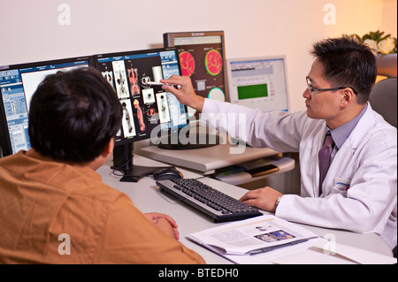 Arzt, PET-CT Diagnostik medizinische Scanner Patientenbilder zu erklären, auf Computer-Monitore im Krankenhaus Büro Stockfoto