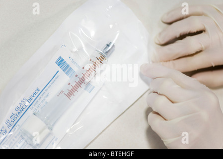 Mitarbeiter öffnen sterile Verpackung mit medizinischen Spritze Stockfoto
