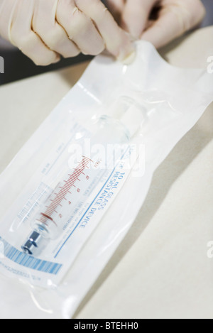Mitarbeiter öffnen sterile Verpackung mit medizinischen Spritze Stockfoto
