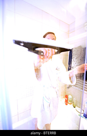 Junge Frau, die Reinigung der Dusche Glastür mit Wischer im Badezimmer Stockfoto