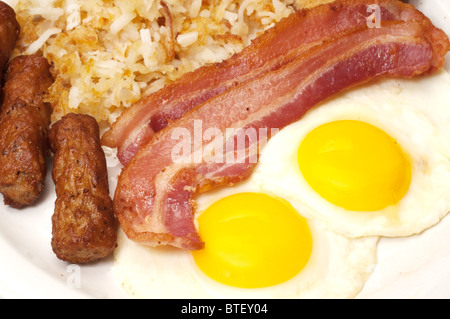 Frühstücksteller mit Eiern sonnigen Seite nach oben, Speck, Wurst Link und Rösti. Stockfoto