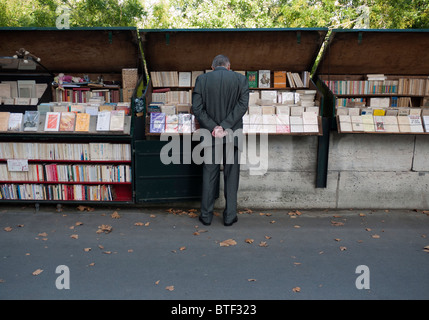 Mann im Buch durchsuchen Stände auf Bürgersteig neben Fluss im Zentrum von Paris Frankreich Stockfoto