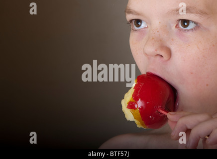 Kind einen Glasierter Apfel essen Stockfoto