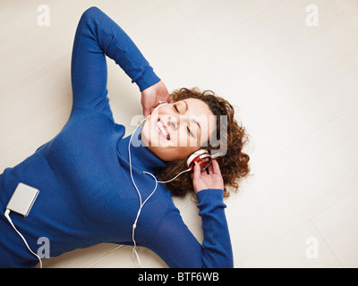 Frau mit Kopfhörern am Boden liegend Stockfoto