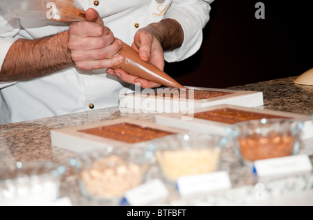 Ein Koch gießt Schokolade in die Fächer Lindt Schokolade zu machen, "Salon du Chocolat", Paris, Frankreich Stockfoto