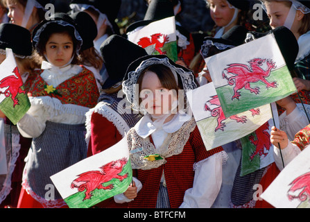 Walisische Kinder gekleidet in traditioneller Tracht mit roter Drache walisische Fahnen zum jährlichen St. Davids Tag feiern, Wales, UK Stockfoto