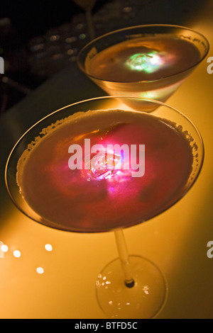 Ginger Cosmo, ein alkoholisches Getränk, beleuchtet von einer Kunststoff Eiswürfel, die Farbe ändert Stockfoto