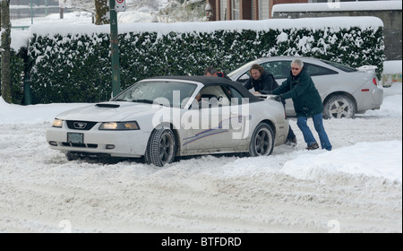 Vancouver Wetter oft entsteht eine Situation, wo ein Auto im Schnee und Menschen Hilfe drücken es streckte ist. Stockfoto