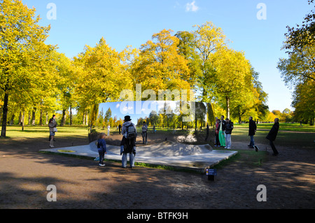 Besucher, die in den Kensington Gardens sind, sehen reflektierte Bilder von sich selbst in einem der Anish Kapoor Sky Mirrors C Curve London England UK Stockfoto