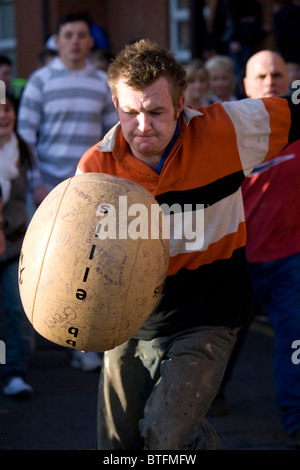 Atherstone Ballspiel. Zwei Teams versuchen, kick und tragen einen Lederball an beiden Enden der Long Street am Faschingsdienstag Stockfoto