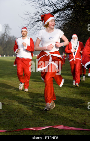 Frau / Frau Läufer / läuft / läuft als Santa Claus / Weihnachtsmann in einer Wohltätigkeitsorganisation gesponsert Volkslauf. Stockfoto