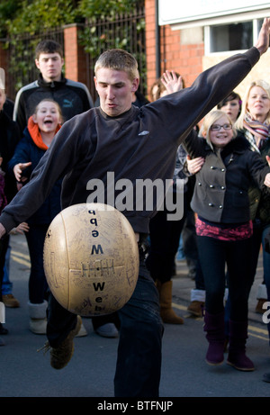 Atherstone Ballspiel. Zwei Teams versuchen, kick und tragen einen Lederball an beiden Enden der Long Street am Faschingsdienstag Stockfoto