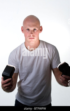 Glatzkopf (20-25) in einem weißen t-Shirt und weißem Hintergrund halten Sie drahtlose Kamera blinkt. Stockfoto