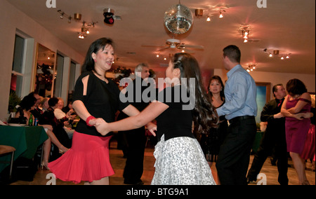 Diese ziemlich Asian Frau in einem roten Rock ist Gesellschaftstanz mit jüngeren Mädchen, helfen, Lehren und Praxis Tanz auf der Tanzfläche Stockfoto