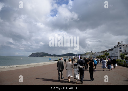 Hochzeitsgäste Fuß entlang der Abschlussball in Llandudno Stockfoto