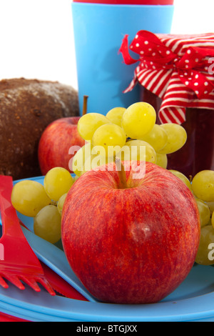 Picknick mit Brot und Obst auf roten und blauen Kunststoff-Geschirr Stockfoto