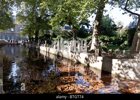 Leute sitzen entlang der Becken Medici-Brunnen im Jardin du Luxembourg Ruhe genießen & gefiltertes Licht auf Herbst Blätter Stockfoto