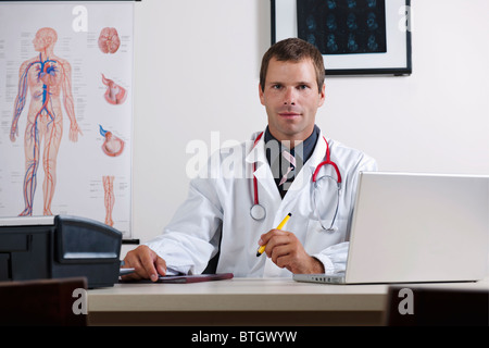 Arzt in seinem Büro mit Herz-Kreislauf-System-Chart und laptop Stockfoto
