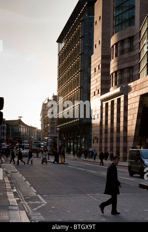 Fußgänger überqueren Queen Victoria Street mit einer Einstellung Sonne Gießen Licht auf das Bürogebäude, London, England. Stockfoto