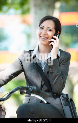 Frau im Anzug mit dem Fahrrad am Handy sprechen Stockfoto