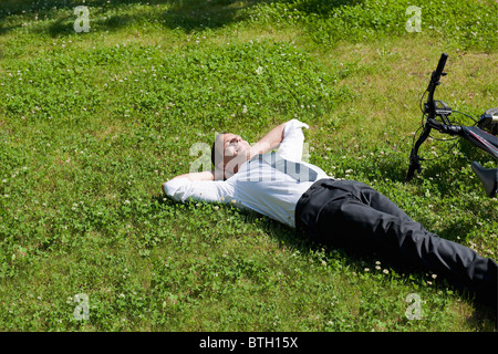 Geschäftsmann Gras neben dem Fahrrad genießen Sie die Sonne liegend Stockfoto