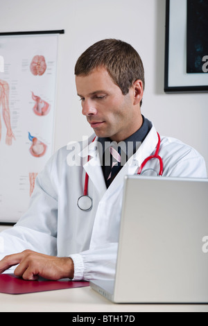 Arzt in seinem Büro mit Herz-Kreislauf-System-Chart und laptop Stockfoto