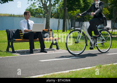 Geschäftsfrau auf Fahrrad vorbei ein Geschäftsmann im freien Stockfoto