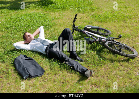 Geschäftsmann Gras neben dem Fahrrad genießen Sie die Sonne liegend Stockfoto