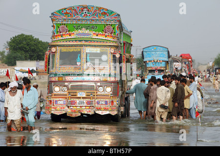 Menschen gehen durch überflutete Straßen, Muzaffergar, Pakistan Stockfoto